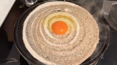 Crispy ghee karam onion egg dosa topped with onions and podi